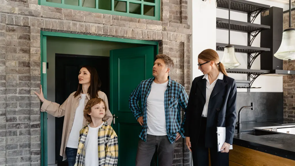 A real estate agent showing a home to a family at the front door.