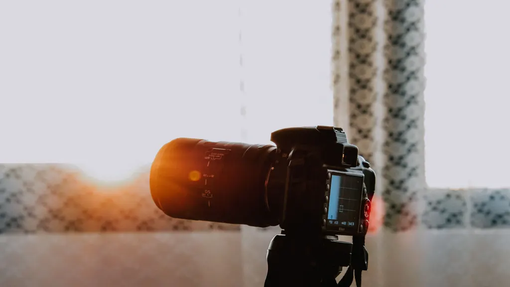 A camera on a tripod photographing a sunlit room.