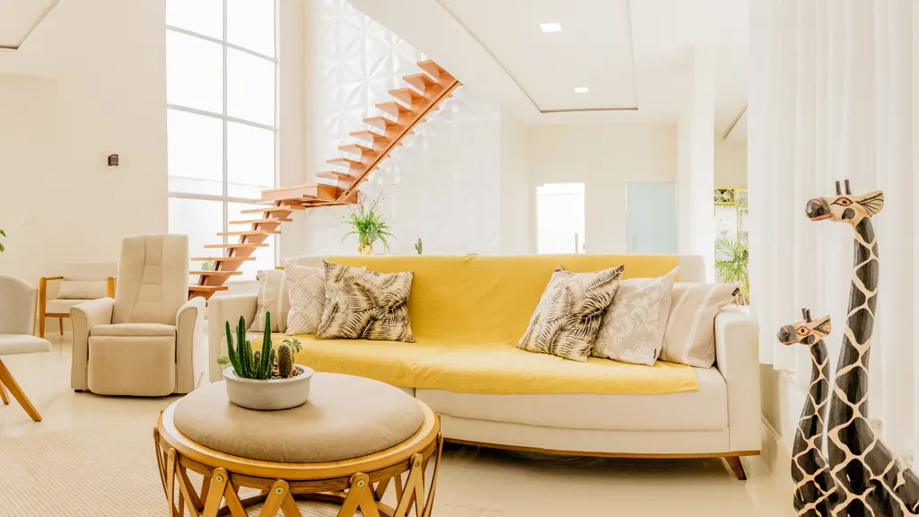 A staged living room with a yellow sofa, armchairs and a round coffee table.