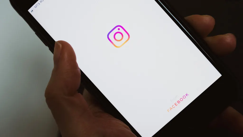 A hand holding a phone with the Instagram app open on screen.
