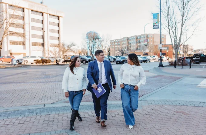 David Mendez and two Realproz agents walking side by side along a downtown sidewalk on a clear winter day, David carrying a Realproz-branded folder.